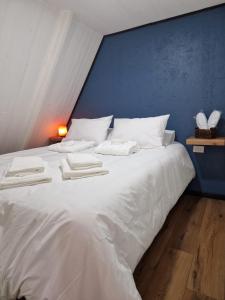 Una gran cama blanca en una habitación con una pared azul. en Ecos del Manantial, en Villarrica