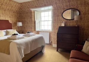 a bedroom with a bed and a mirror and a dresser at The Manor House Hotel in Oban