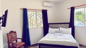a bedroom with a bed and a chair and two windows at City Suite Apartment Cabrera in Cabrera