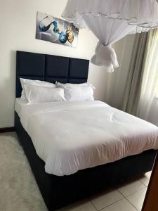 een bed met witte lakens en kussens in een slaapkamer bij Pacho- All en-suite 2br in Kisumu