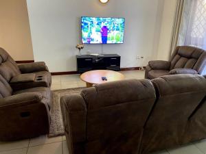 a living room with two couches and a flat screen tv at Pacho- All en-suite 2br in Kisumu