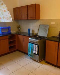 a kitchen with a stove and wooden cabinets at Pacho- All en-suite 2br in Kisumu