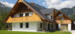a house with a wooden roof with mountains in the background at PRIVILLAGE Stare - Villa & Chalet in Bohinj