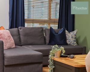 un sofá gris con almohadas en la sala de estar en Three Bedroom House By PureStay Short Lets & Serviced Accommodation Manchester With Free Parking, en Mánchester