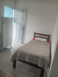 Cama en habitación blanca con ventana en Suíte Canto Caiçara, en Ubatuba