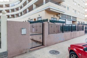 een rode auto geparkeerd voor een gebouw met een hek bij Elegante apartamento muy cerca de la playa in Valencia