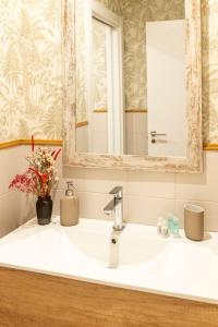 w łazience znajduje się umywalka z lustrem i kwiatami. w obiekcie OT Residence 5 bedrooms 4 bathrooms luxury apartment in Old Town w mieście Bilbao