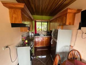 cocina con nevera blanca y armarios de madera en TucanTico Lodge - Monteverde, en Monteverde