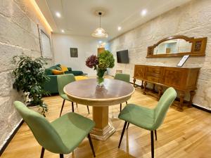 a living room with a table and green chairs at A Michelena de Pedra in Pontevedra