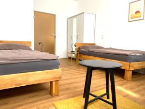 two beds in a room with a table and a stool at Alles komplett: Zwei Schlafzimmer, große Küche, eigenes Bad in Cologne