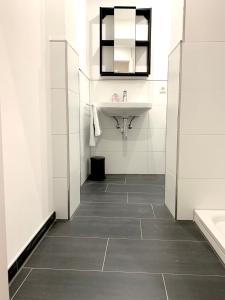 ein weißes Badezimmer mit einem Waschbecken und einem Spiegel in der Unterkunft Alles komplett: Zwei Schlafzimmer, große Küche, eigenes Bad in Köln
