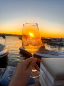 une personne tenant un verre de vin au coucher du soleil en arrière-plan dans l'établissement Sicily O’Clock House, à Lentini