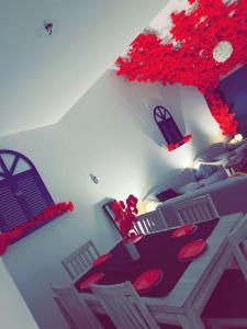 1 dormitorio con 1 cama y 1 mesa con flores rojas en منتجع شاطيء جوفالي GUVALI Beach شاليه طراز ميكانوس Siyal سيال سابقاً, en Yeda