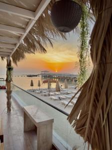 een uitzicht op een strand met een bank en de zonsondergang bij منتجع شاطيء جوفالي GUVALI Beach شاليه طراز ميكانوس Siyal سيال سابقاً in Jeddah