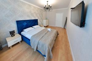 1 dormitorio con 1 cama grande y TV en Apartment Lazurniy 7Б en Astaná
