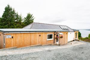 a large wooden building with a garage at Luxury Cottage With Stunning Views Near Fairy Pools! in Carbost