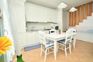 a white kitchen with a white table and chairs at Appartamenti Arcobaleno in Casa Bullo