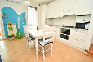 a kitchen with white cabinets and a white table and chairs at Appartamenti Arcobaleno in Casa Bullo