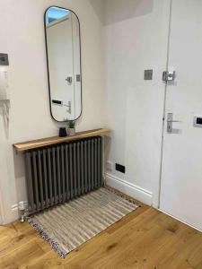 Top Floor Flat - Glasgow West End - Partick في غلاسكو: غرفة بها مشعاع ومرآة على الحائط