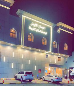 two cars parked in front of a building at night at الجناح الأبيض للأجنحه الفندقية in Dammam