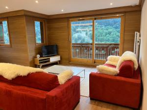 a living room with two red couches and a television at Newly renovated 7-9pers Luxury Chalet in Meribel Centre 85m2 3BR 3BA with stunning Mountain View in Méribel