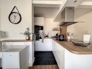 a kitchen with white cabinets and a clock on the wall at Escale de Charme à Brest - Hypercentre - Cocon de calme et de confort in Brest