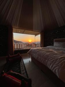 a bedroom with a bed and a view of the sunset at Zawaideh desert Camp in Wadi Rum +75 photos