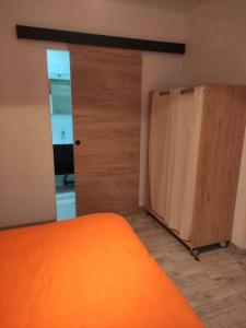 um quarto com uma cama laranja e uma porta em Chez Nathalie em La Celle-sur-Loire