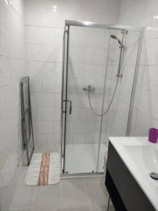 uma casa de banho branca com um chuveiro e um lavatório. em Chez Nathalie em La Celle-sur-Loire