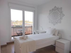 Habitación blanca con cama y balcón. en Apartamento PATXIKE con plaza de garaje en Bermeo