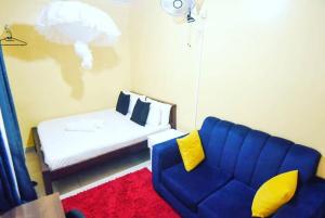 sala de estar con sofá azul y cama en Pacho Studio-2, en Kisumu