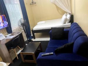 sala de estar con sofá azul y cama en Pacho Studio-2, en Kisumu