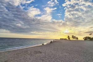 a beach with palm trees and the ocean at sunset at Lovely condo at Blue Sea Tower near Juan Dolio beach in Juan Pedro