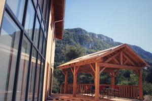 a wooden gazebo with tables and chairs next to a building at Aux Buis Gourmands in La Chapelle-en-Vercors