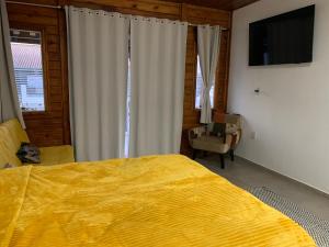 a bedroom with a large yellow bed and a chair at Canto Gira Sol - Suíte Flor in Penha