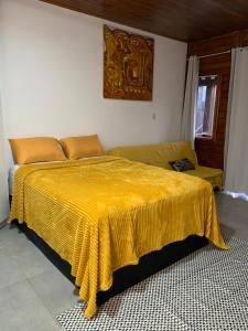 a bedroom with a bed with a yellow blanket on it at Canto Gira Sol - Suíte Flor in Penha