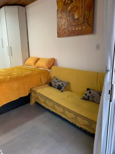 a living room with a couch and a bed at Canto Gira Sol - Suíte Flor in Penha