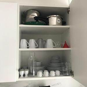 a cupboard filled with dishes and cups and plates at STUDIO "Helvetia Star" in Zürich-Pfaffhausen in Pffaffhausen
