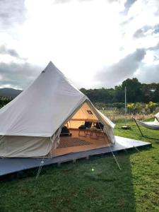 Maleka Farm: Tent Glamping North Shore Oahu في Laie: خيمة كبيرة مع سطح في ميدان
