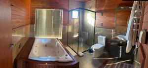 y baño con bañera, ducha y aseo. en Vinícola D'alture - Cabana Familiar en São Joaquim
