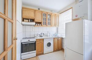 eine Küche mit Holzschränken und einem weißen Kühlschrank in der Unterkunft Old Town apartment in Kaunas