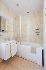 a white bathroom with a tub and a sink at Old Town apartment in Kaunas
