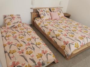 ein Schlafzimmer mit zwei Betten mit rosa und gelben Blumen in der Unterkunft Chambre d'hôte in Grabels