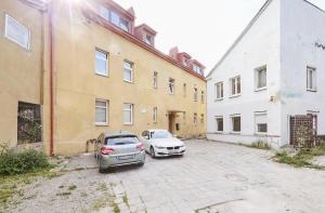 zwei Autos auf einem Parkplatz neben Gebäuden geparkt in der Unterkunft Old Town apartment in Kaunas