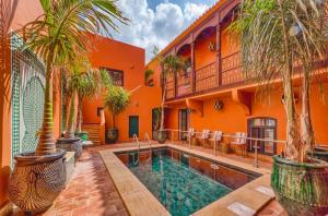 an orange house with a swimming pool and palm trees at Casa Riad Yasmin in Silves