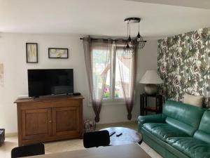 ein Wohnzimmer mit einem grünen Sofa und einem TV in der Unterkunft Agréable maison avec jolie terrasse extérieure in Champigneulles