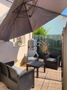 eine Terrasse mit einem Sonnenschirm, Stühlen und einem Tisch in der Unterkunft Agréable maison avec jolie terrasse extérieure in Champigneulles