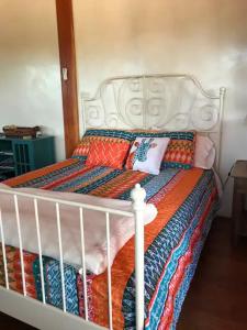 ein weißes Bett mit einer bunten Decke und Kissen darauf in der Unterkunft Casita Luna in Santa Fe
