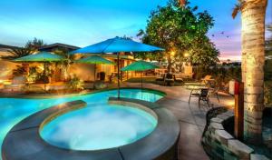 een zwembad met parasols en een patio bij Desert Retreat Oasis in La Quinta