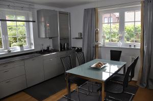 d'une cuisine avec une table, des chaises et des fenêtres. dans l'établissement Aquarell, à Schönberger Strand